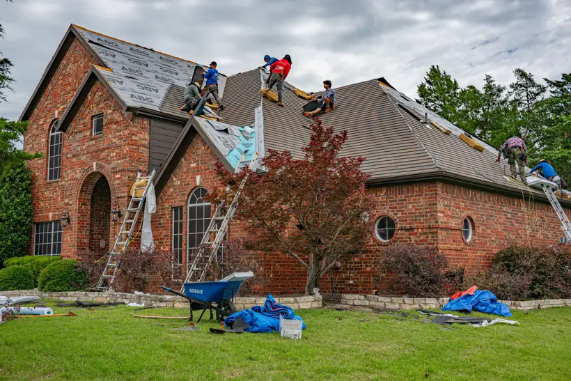 Crew replacing the roof on a two-story brick home