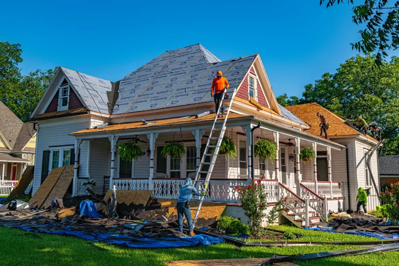 Roofers on a historic Victorian home with a wraparound porch
