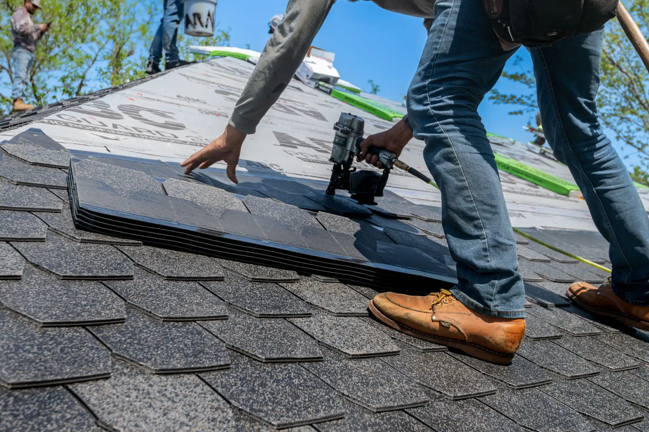 Roofer nailing new architectural shingles