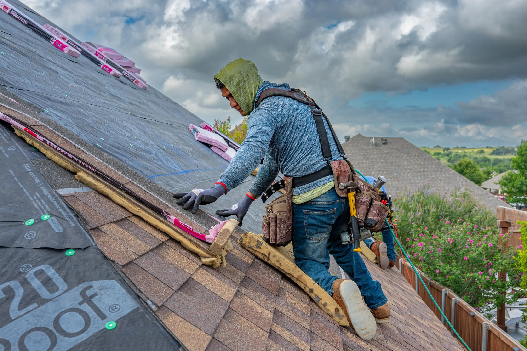 Roofer working on underlayment and new shingles on a Texas home